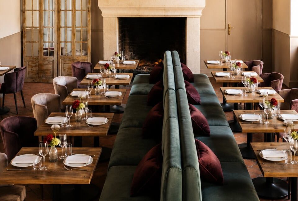 Salle du restaurant La Table des Époisses en Seine-et-Marne, avec sa cheminée en pierre et ses banquettes de velours